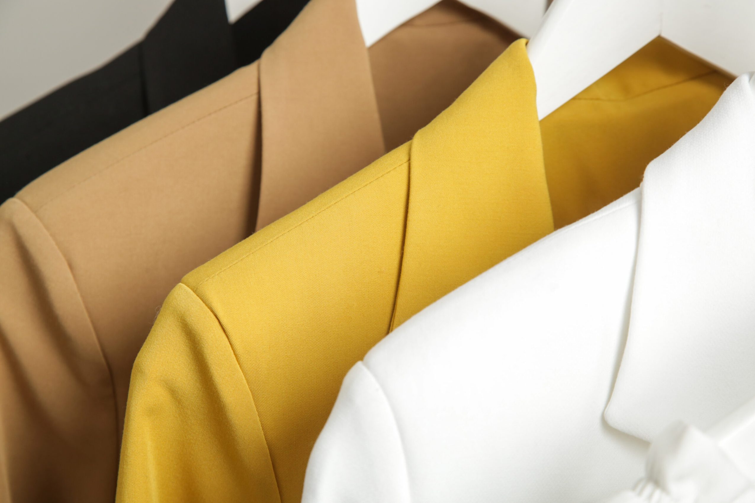 Close up image of fashionable tailored blazers hanging on a rack